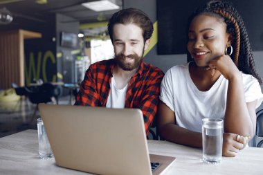 Birlikte çalışan gençler dizüstü bilgisayarlarını kullanıyorlar.