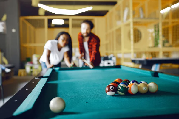 Casal internacional jogando um bilhar em um clube — Fotografia de Stock