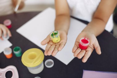 İki küçük kız sınıfta oturuyor ve resim çiziyor.