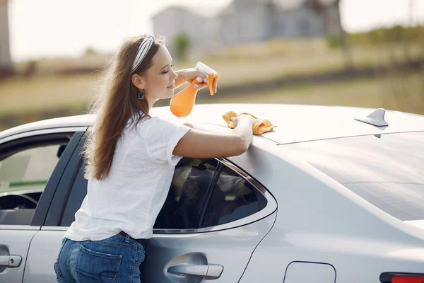 Elegante donna pulisce l'auto con uno straccio — Foto Stock