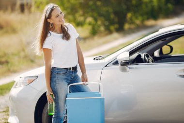 Arabanın yanında duran zarif kadın.