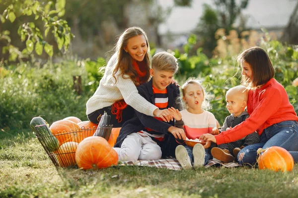 Big family sitting on a garden near many pumpkins — Stock Photo, Image
