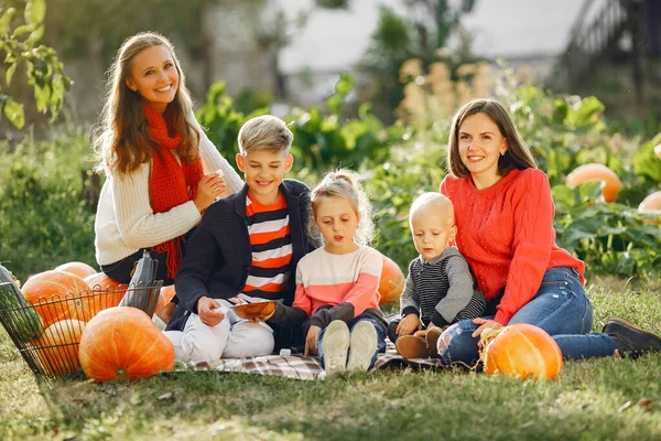 Big family sitting on a garden near many pumpkins