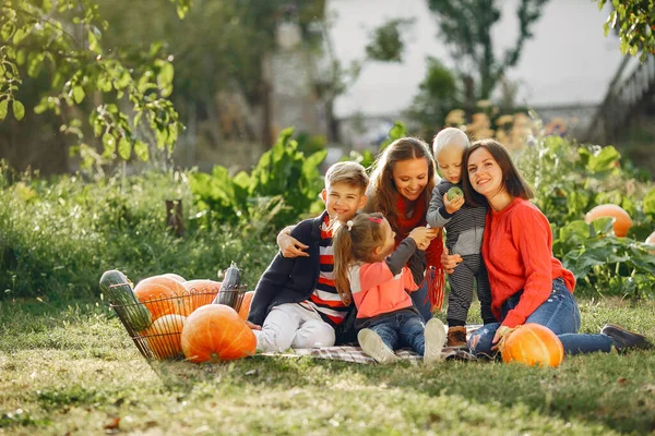 Big family sitting on a garden near many pumpkins