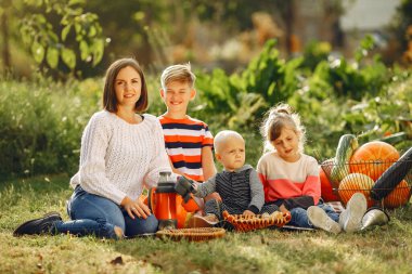 Balkabaklarının yanındaki bahçede oturan büyük bir aile.