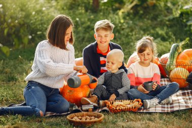 Balkabaklarının yanındaki bahçede oturan büyük bir aile.
