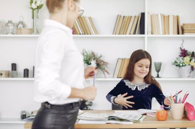 Küçük kızla evde ders çalışan bir öğretmen.