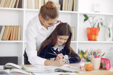 Küçük kızla evde ders çalışan bir öğretmen.