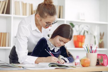 Küçük kızla evde ders çalışan bir öğretmen.