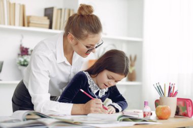 Küçük kızla evde ders çalışan bir öğretmen.