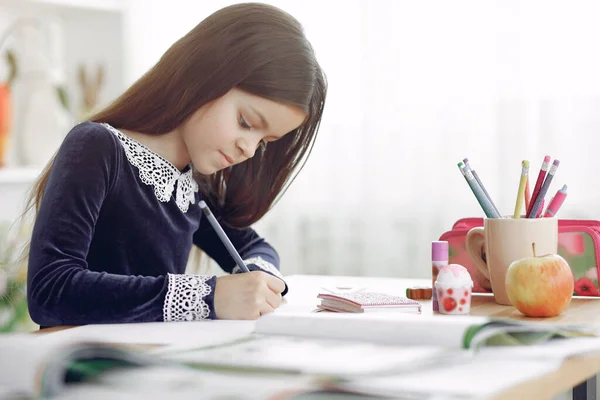 Bambina seduta su un tavolo con libri — Foto Stock