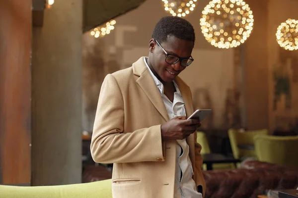 Schwarzer Mann in braunem Mantel mit Handy — Stockfoto