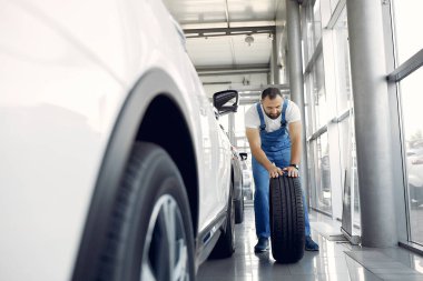 Mavi üniformalı yakışıklı adam arabayı kontrol ediyor.