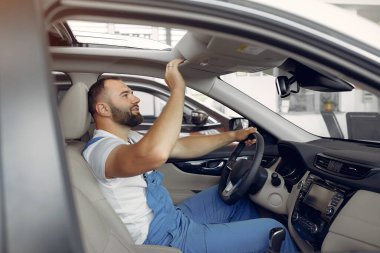 Mavi üniformalı yakışıklı adam arabayı kontrol ediyor.