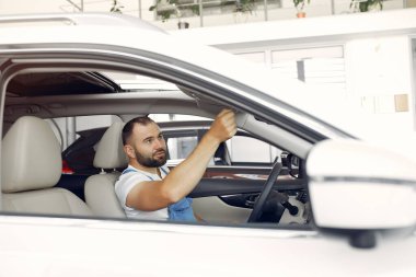 Mavi üniformalı yakışıklı adam arabayı kontrol ediyor.