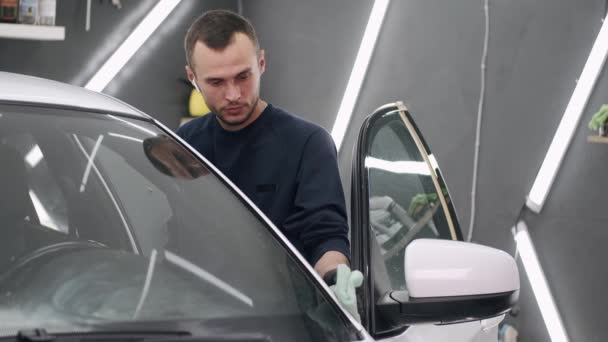 Man poets een auto in een garage — Stockvideo