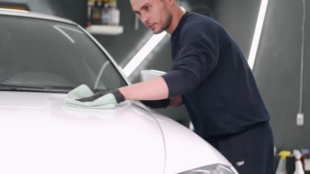 Man poets een auto in een garage — Stockvideo