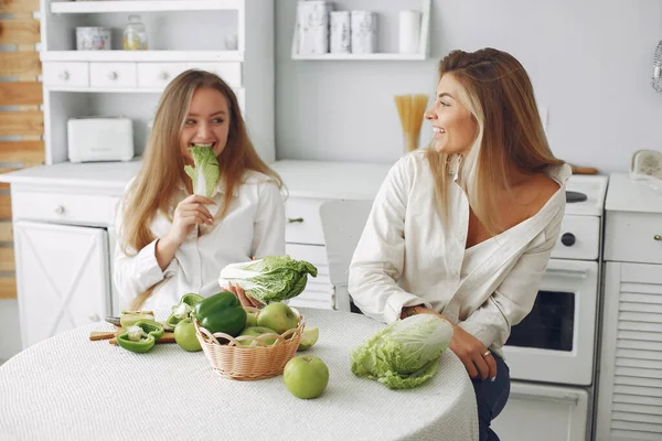 Meninas bonitas e desportivas em uma cozinha com um legumes — Fotografia de Stock