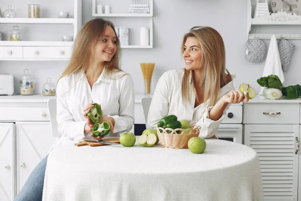 Meninas bonitas e desportivas em uma cozinha com um legumes — Fotografia de Stock