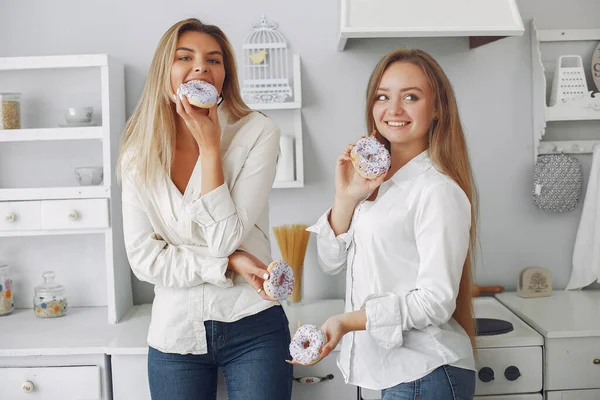 Hermosa chica de pie en una cocina con donut — Foto de Stock