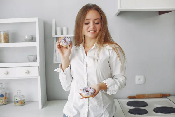 Menina bonita de pé em uma cozinha com donut — Fotografia de Stock