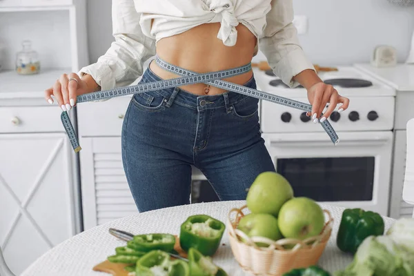 Vacker och sportig flicka i ett kök med grönsaker — Stockfoto