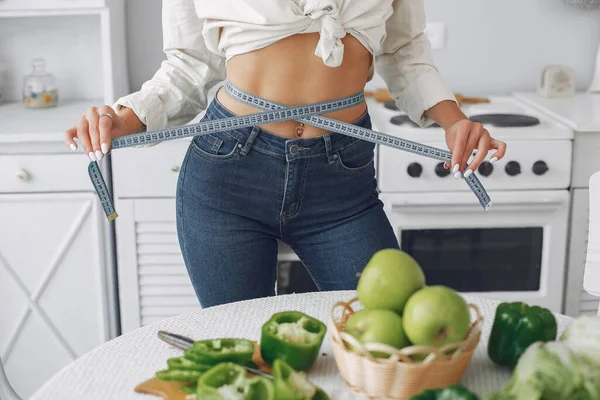 Mooi en sportief meisje in een keuken met een groente — Stockfoto