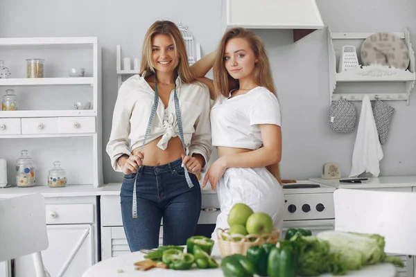 Mooie en sportieve meisjes in een keuken met een groente — Stockfoto