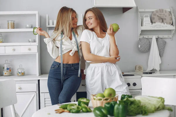 Meninas bonitas e desportivas em uma cozinha com um legumes — Fotografia de Stock