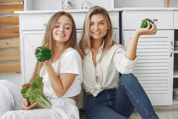 Vackra och sportiga tjejer i ett kök med grönsaker — Stockfoto