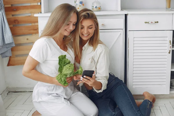 Meninas bonitas e desportivas em uma cozinha com um legumes — Fotografia de Stock