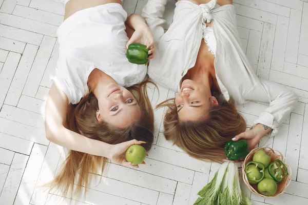 Beautiful and sporty girls in a kitchen with a vegetables — Stock Photo, Image
