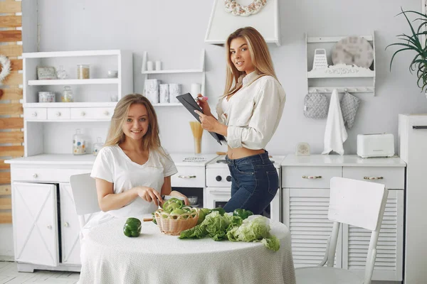 Meninas bonitas e desportivas em uma cozinha com um legumes — Fotografia de Stock