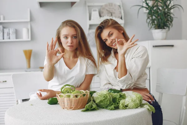 Meninas bonitas e desportivas em uma cozinha com um legumes — Fotografia de Stock