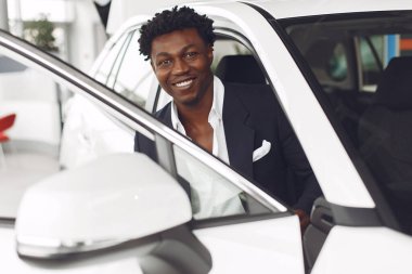 Yakışıklı ve zarif bir siyah adam bir araba salonunda.