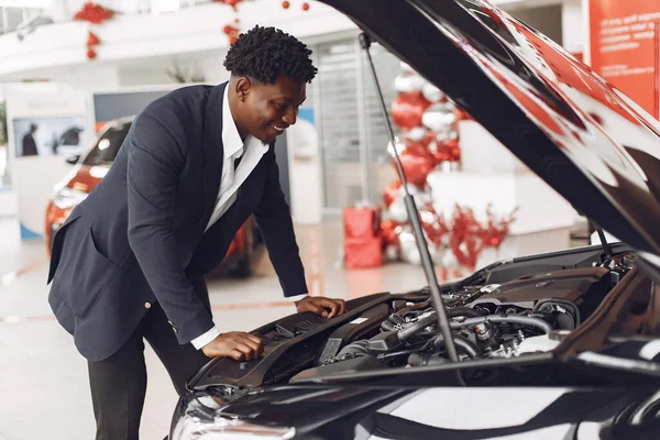 Hombre negro guapo y elegante en un salón de coches —  Fotos de Stock