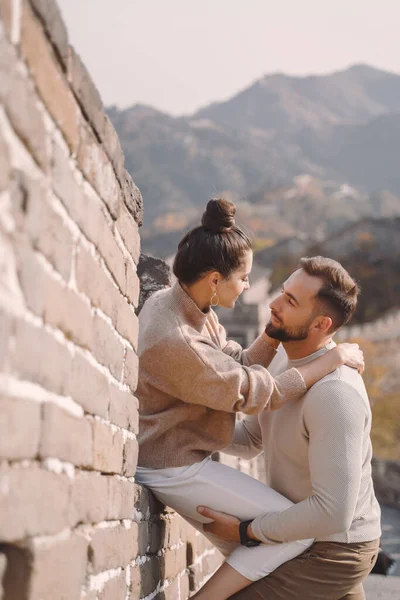 Hermosa pareja joven sentada y mostrando afecto en la Gran Muralla de China . — Foto de Stock