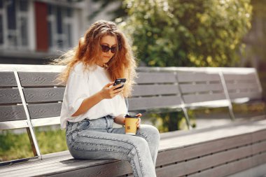 Öğrenciler telefon ve kahveyle şehirde oturuyorlar.