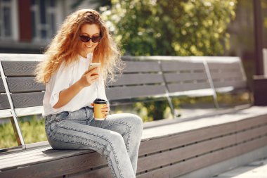 Öğrenciler telefon ve kahveyle şehirde oturuyorlar.