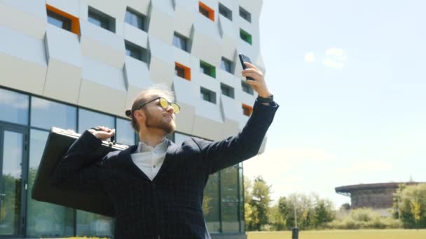 Empresario con maleta caminando en una ciudad de verano — Vídeos de Stock