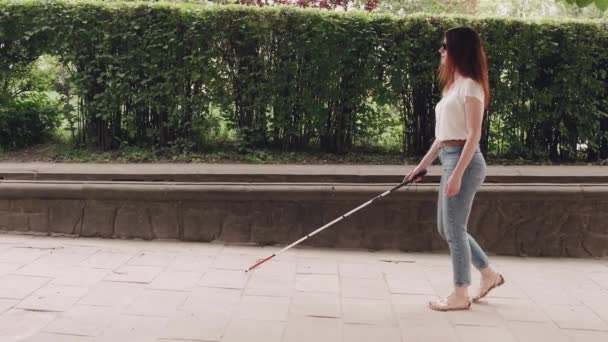 Jong blind persoon met lange wandelstok in een stad — Stockvideo