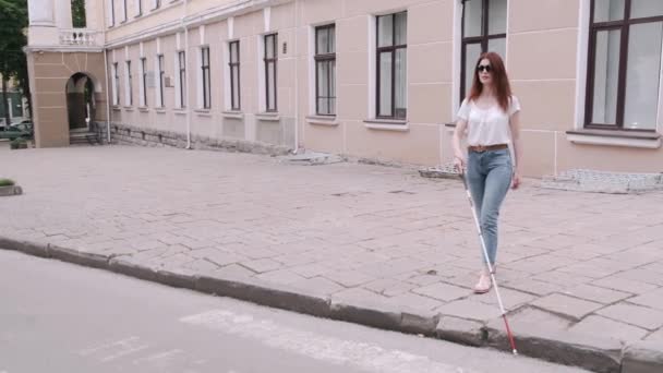 Young blind person with long cane walking in a city — Stock Video