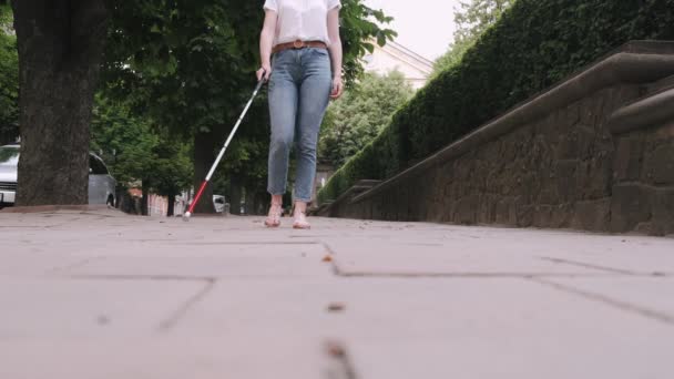 Молода сліпа людина з довгою тростиною, що йде в місті — стокове відео
