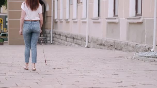 Молодой слепой человек с длинной тростью ходит по городу — стоковое видео