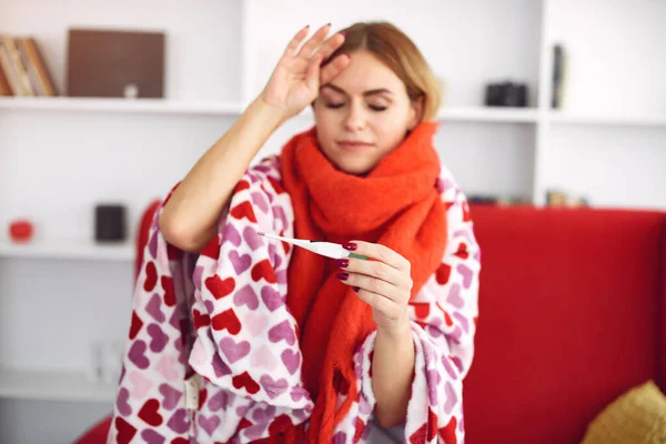 Woman sitting at home with a cold and measures the temperature — Stock Photo, Image