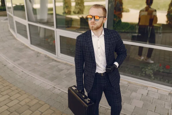 Empresario con maleta caminando en una ciudad de verano — Foto de Stock