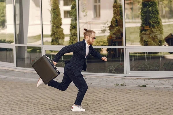 Empresario con maleta caminando en una ciudad de verano — Foto de Stock