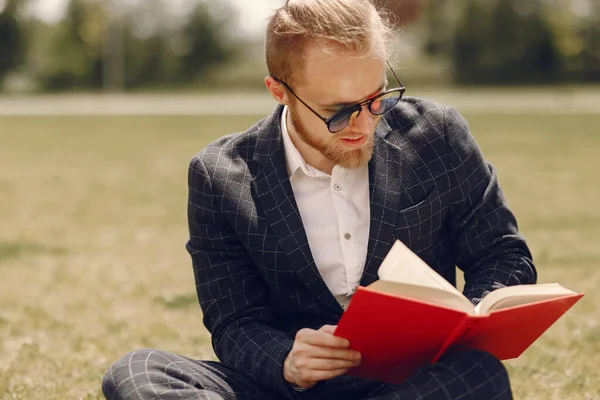 Бізнесмен з книгою сидить у літньому місті — стокове фото