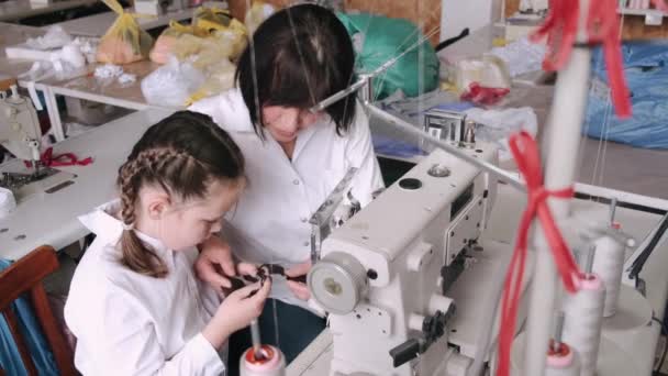 Mormor med lilla barnbarn syr kläder i fabriken — Stockvideo