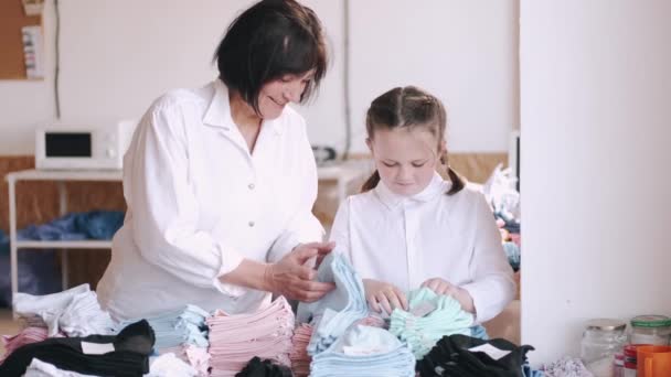 Mormor med lilla barnbarn mäter tyget för sömnad — Stockvideo